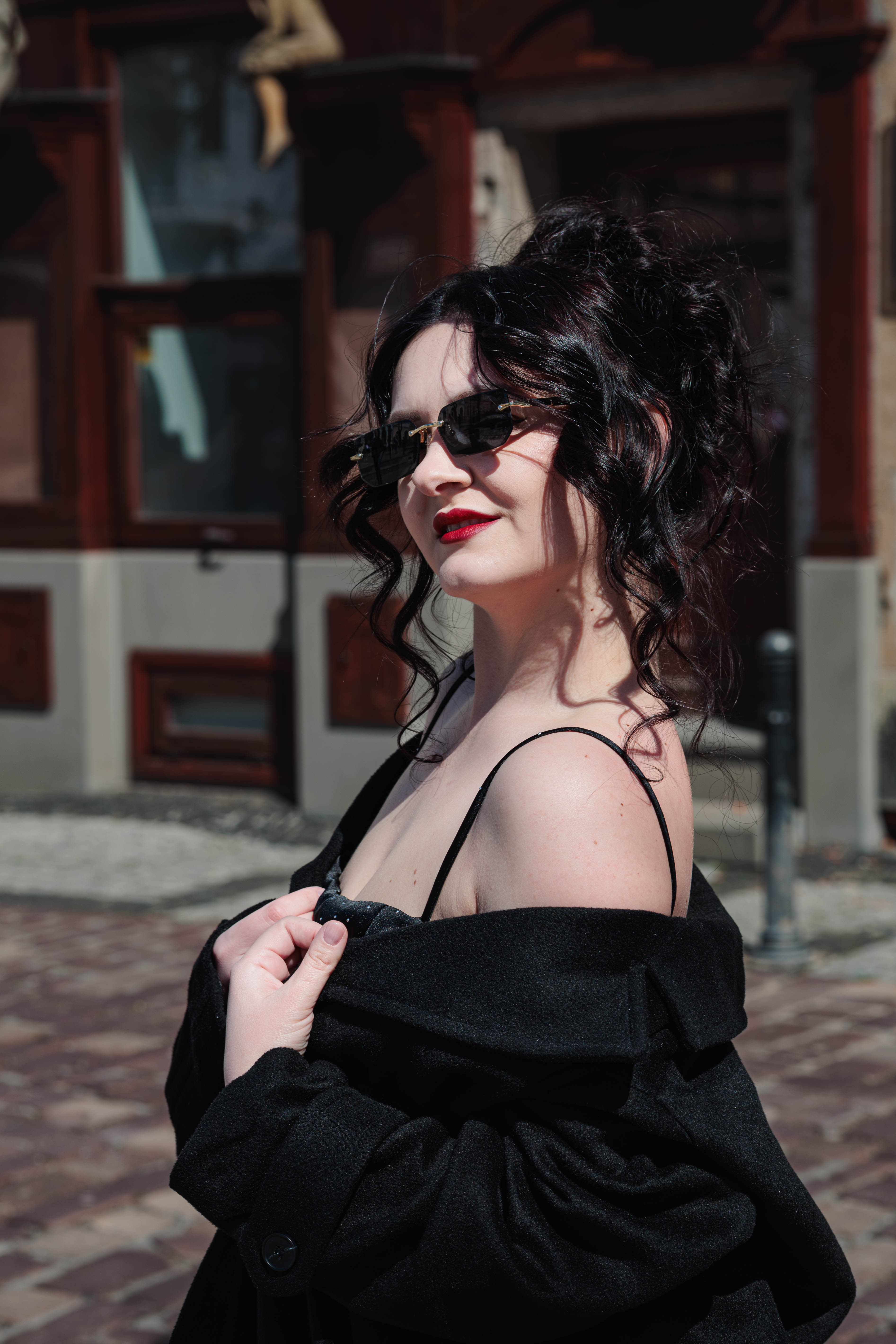 A couple in wedding attire walks hand in hand across a sunlit field.