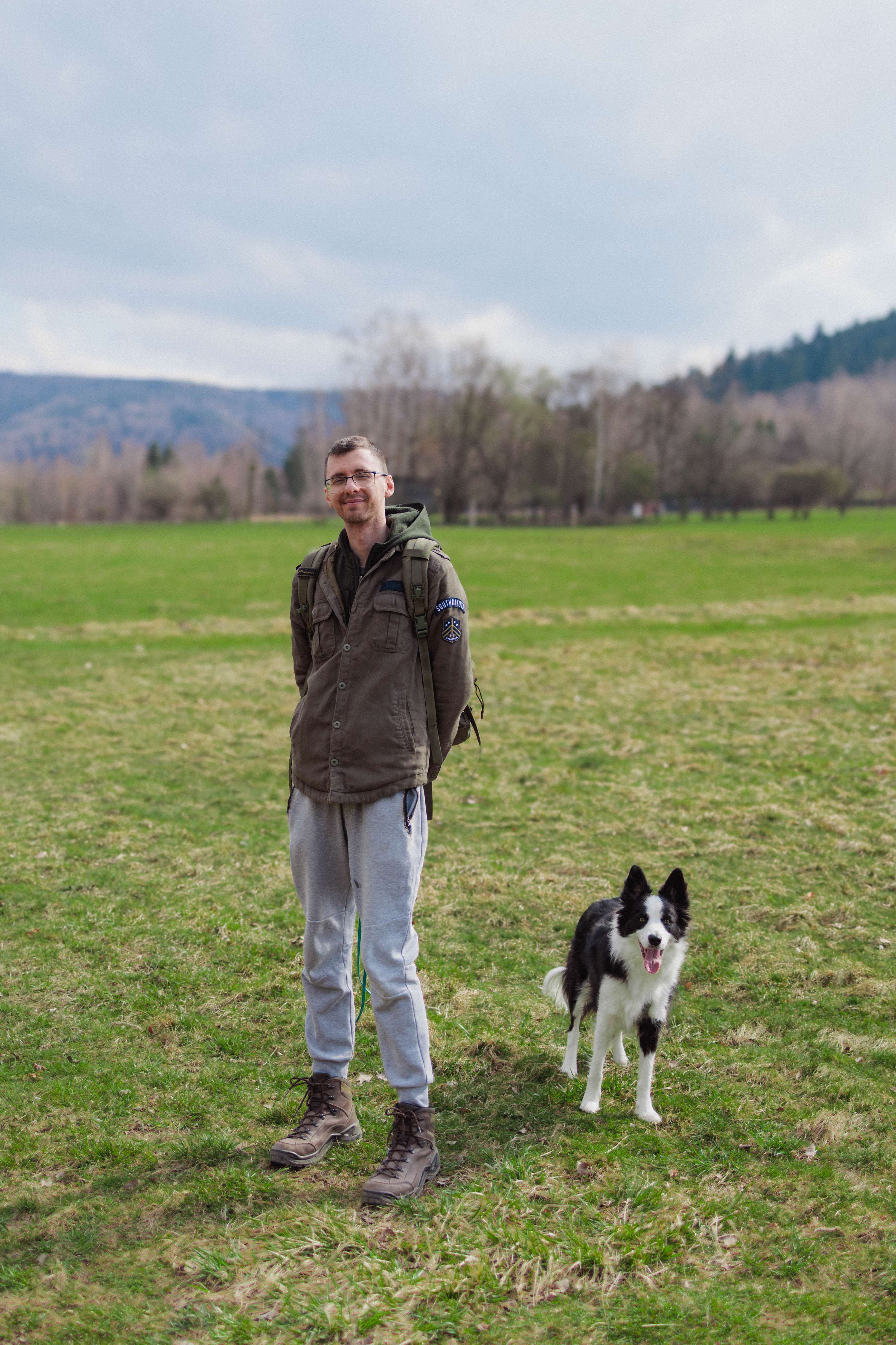 A couple walks hand in hand through a sunlit meadow.