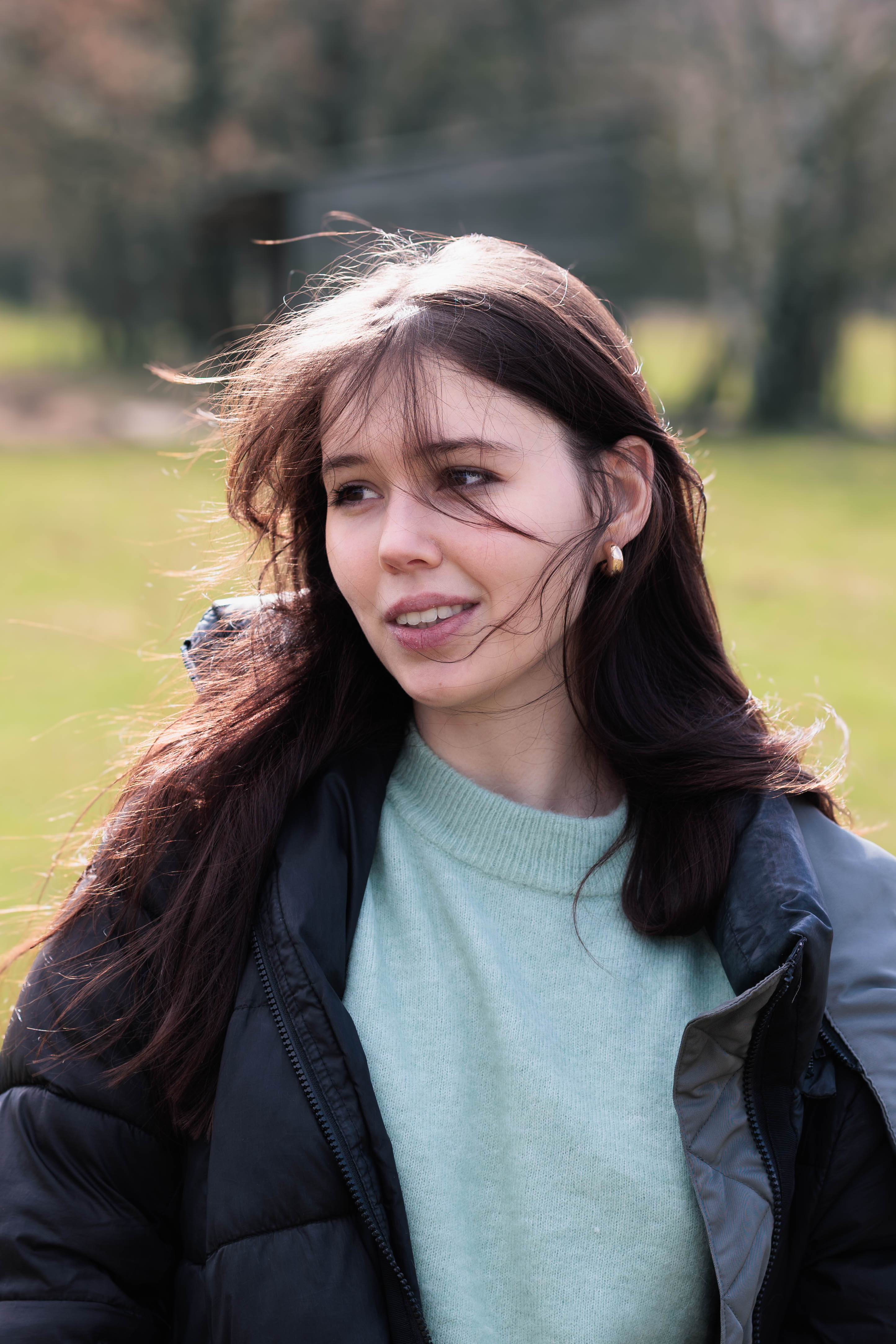 A person with shoulder-length blonde hair wearing a black newsboy cap and a black sweater.